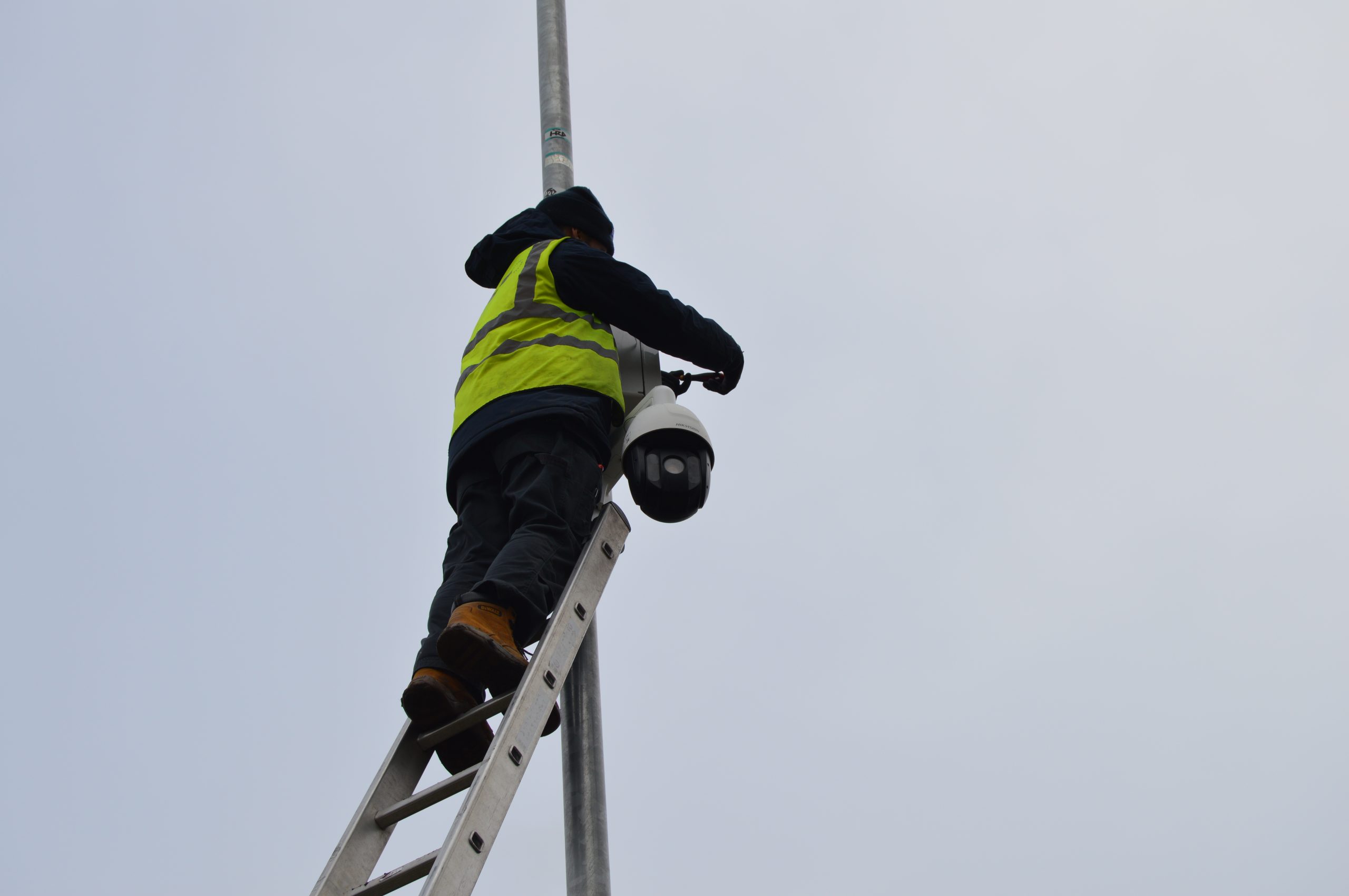 A Link CCTV Systems engineer working up a ladder, installing a camera in Chelmsford.
